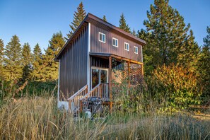 Un chalet rustique avec une façade en bois, une véranda et une vue dégagée sur la forêt environnante.