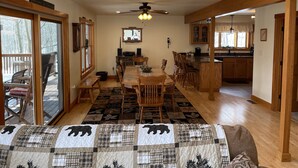A spacious dining area with a wooden table and chairs, a ceiling fan, and a view of the deck through glass doors. - Multi-Family Getaway at Raystown Lake in Central PA (Entriken)