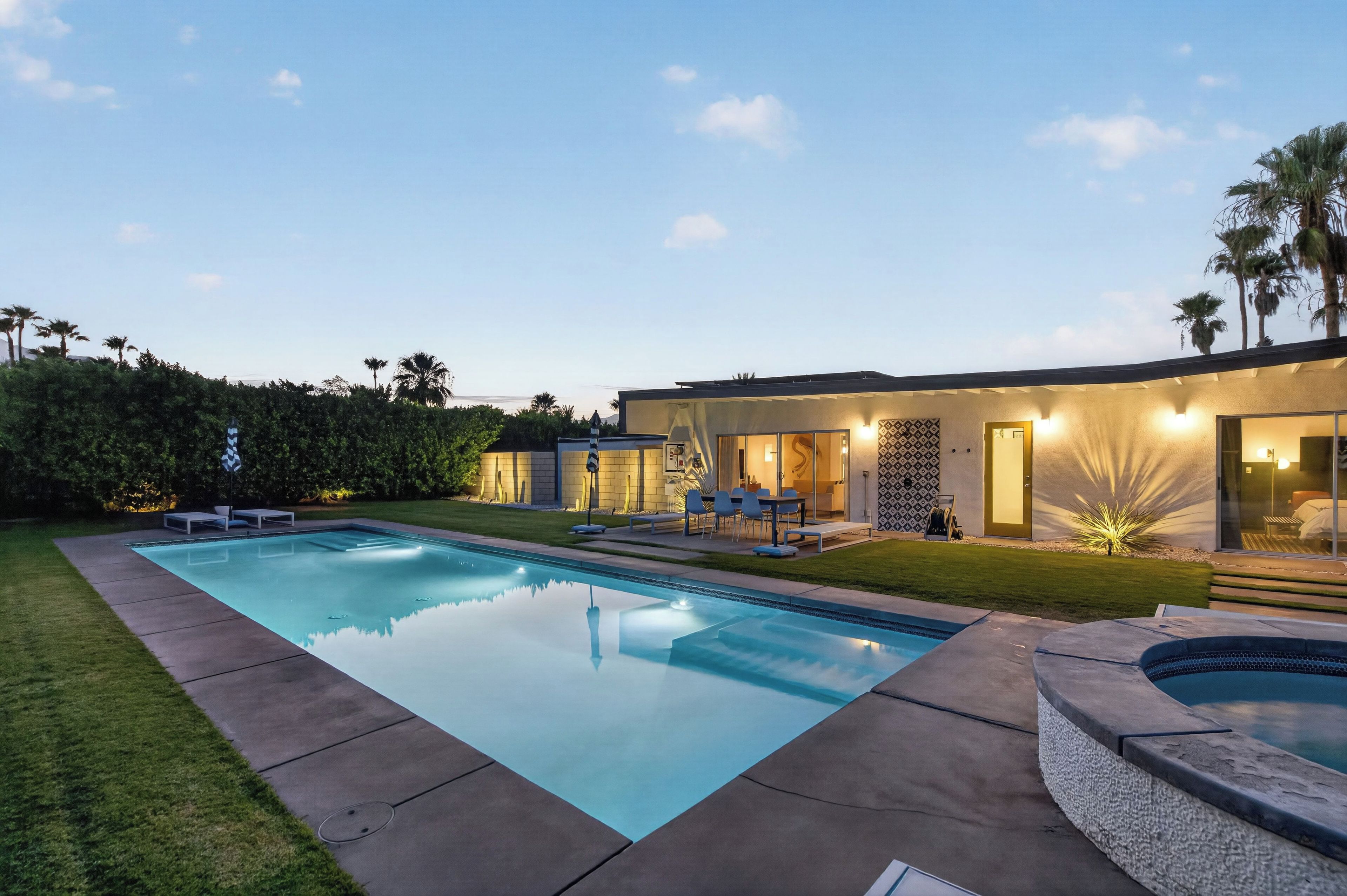 Une maison moderne dotée d’une piscine, d’un espace salon extérieur et d’une pelouse bien entretenue.