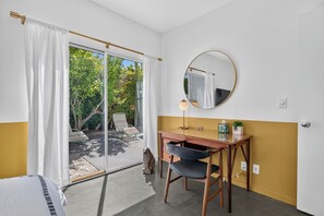 A room with a desk, chair, and a round mirror on the wall.