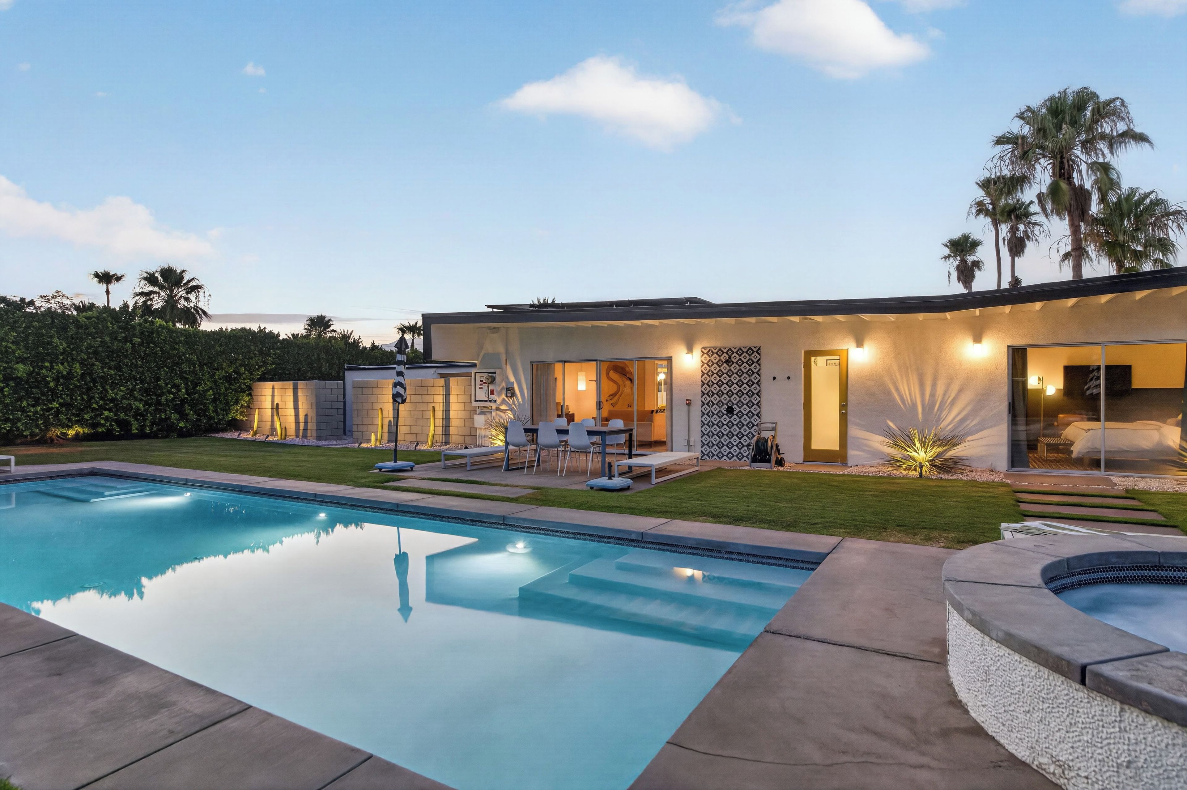 A modern house with a swimming pool, outdoor seating, and a well-maintained garden.