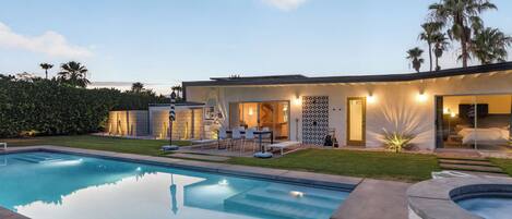 A modern house with a swimming pool, outdoor seating, and a well-maintained garden.