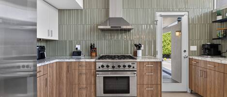 Una cocina moderna con horno empotrado, estufa de acero inoxidable y armarios de madera.
