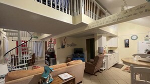 A spacious living area with a high ceiling, a staircase, a kitchen, and a dining area. - Steps To The Beach & 2 Blocks To Downtown Frankfort - Sleeps 6-8 (Frankfort)