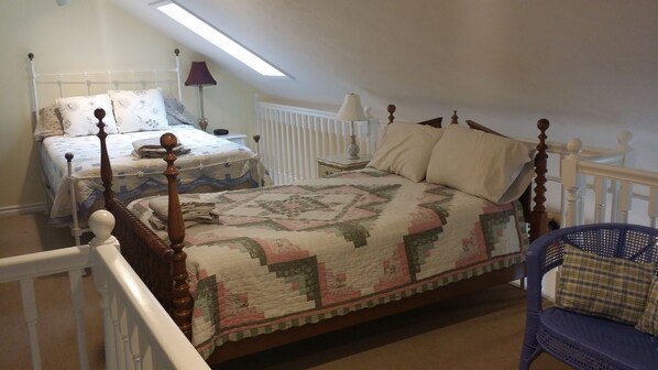 A bedroom with a four-poster bed, a smaller bed, and a chair.