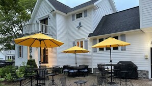A patio with outdoor seating, yellow umbrellas, and a grill. - Steps To The Beach & 2 Blocks To Downtown Frankfort - Sleeps 6-8 (Frankfort)