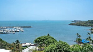 Un port de plaisance où sont amarrés des bateaux, entouré de verdure et offrant une vue dégagée sur la mer.