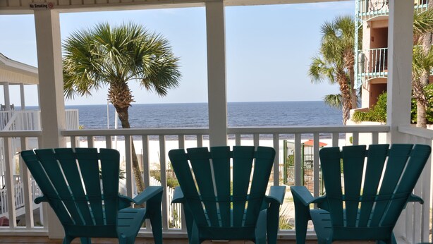 A covered outdoor area with two green Adirondack chairs facing a view of the ocean. - BEACHFRONT PRIVATE COTTAGE, FULL FLOOR, DECK, FREE PARKING BY ENTRANCE, 2BD 2BA  (Panama City Beach)
