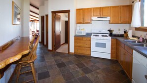 A kitchen with wooden cabinets, a stove, and a dining area with a wooden table and chairs.