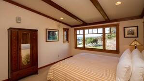 A bedroom with a large bed, wooden wardrobe, and a window with a view.