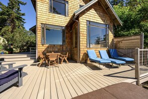 Un terrazzo in legno con tavolo e sedie, e due sdraio.