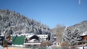 Une montagne enneigée, parsemée de chalets, sous un ciel bleu azur.