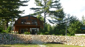 A wooden cabin with a stone wall and a stone staircase leading to the entrance. - Beautifully secluded getaway perfect for all seasons! (Adams)