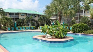 A swimming pool with lounge chairs and a palm tree in the center. - 3 Bedroom Cayman Condo on Seven Mile Beach!  (George Town)