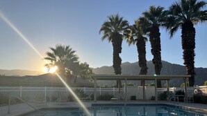 Una piscina con vistas a montañas, palmeras y un pabellón.
