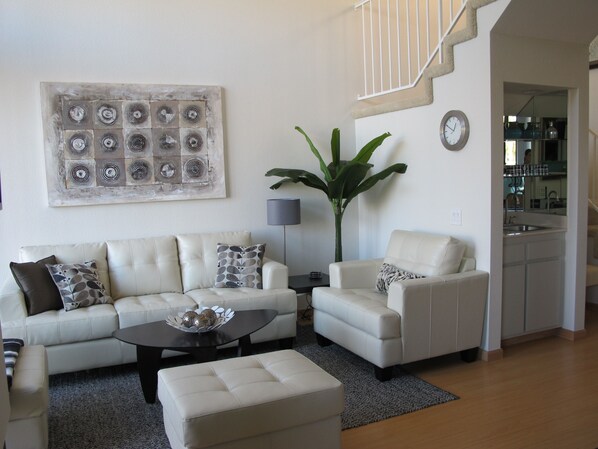 A modern living room with a sofa, armchair, coffee table, and a large abstract painting.