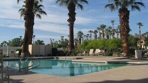 Una piscina con palmeras y sillas de descanso.