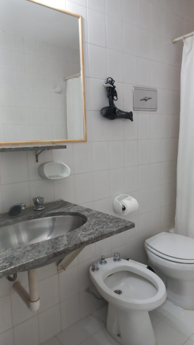 A bathroom with a granite sink, a toilet, a bidet, and a towel rack.