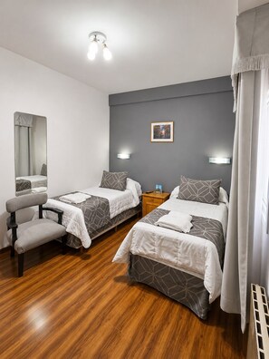 A hotel room with two beds, a chair, a mirror, a picture on the wall, and a ceiling light fixture.
