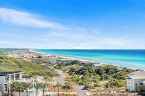 Una zona residencial costera con casas, un camino sinuoso y una playa al fondo.