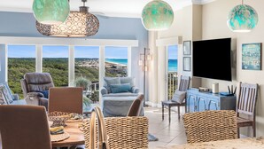 A spacious living room with a large TV, comfortable seating, and a view of the ocean. - Tops`l Beach Manor 803 - Gorgeous Views! (Miramar Beach)