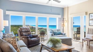 A spacious living room with a view of the ocean, a ceiling fan, and a balcony with a chair. - Tops`l Beach Manor 803 - Gorgeous Views! (Miramar Beach)