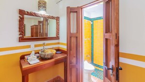 A bathroom with a wooden door, a mirror, and a sink with a bowl. - One Bedroom Suite, Serene, Pool, Gardens, Rooftop Terrace with Views (Isla Mujeres)