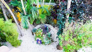 A garden with various plants, a stone fountain, and a yellow wall in the background. - One Bedroom Suite, Serene, Pool, Gardens, Rooftop Terrace with Views (Isla Mujeres)