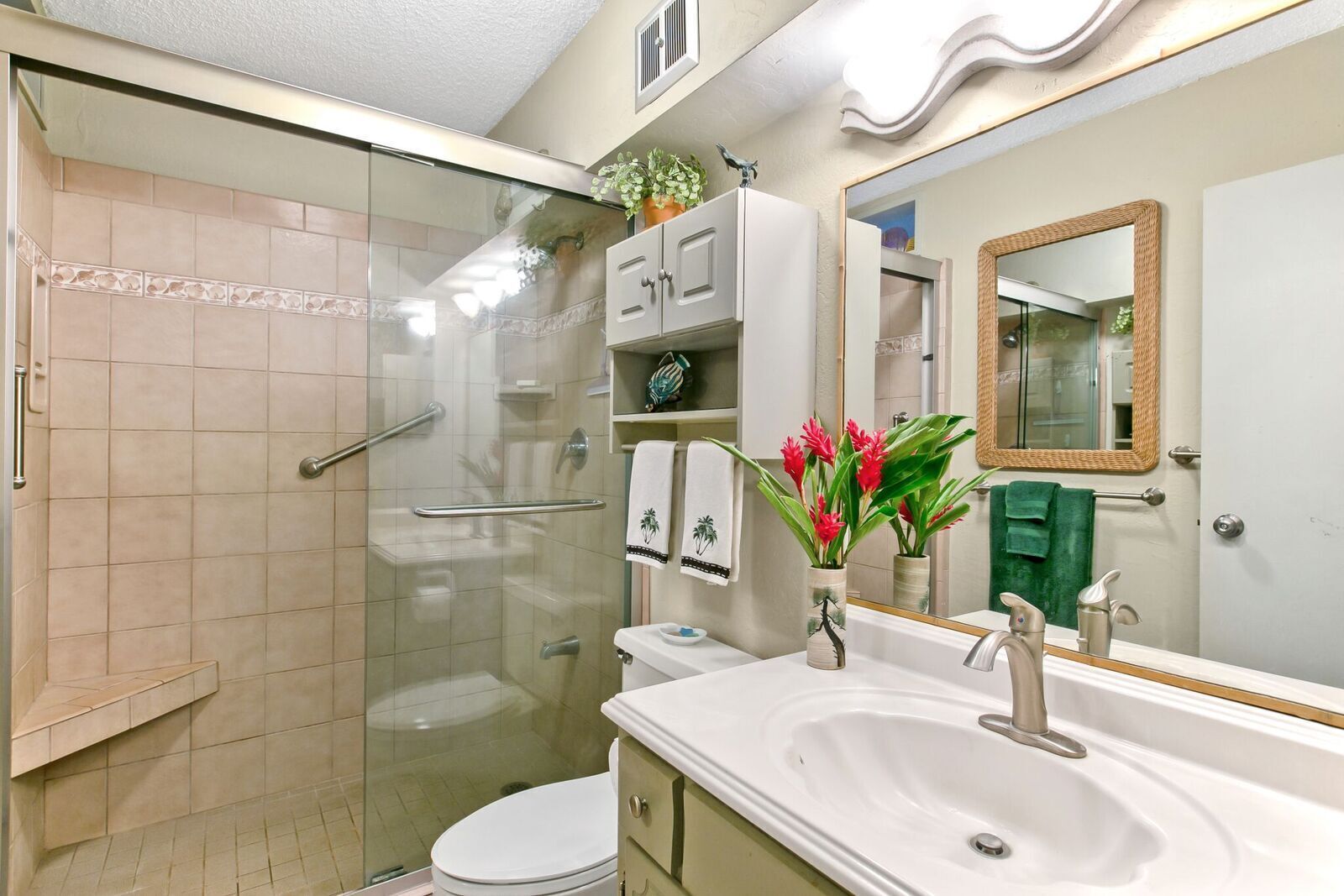 A modern bathroom with a glass shower enclosure, a white sink, and a vanity.