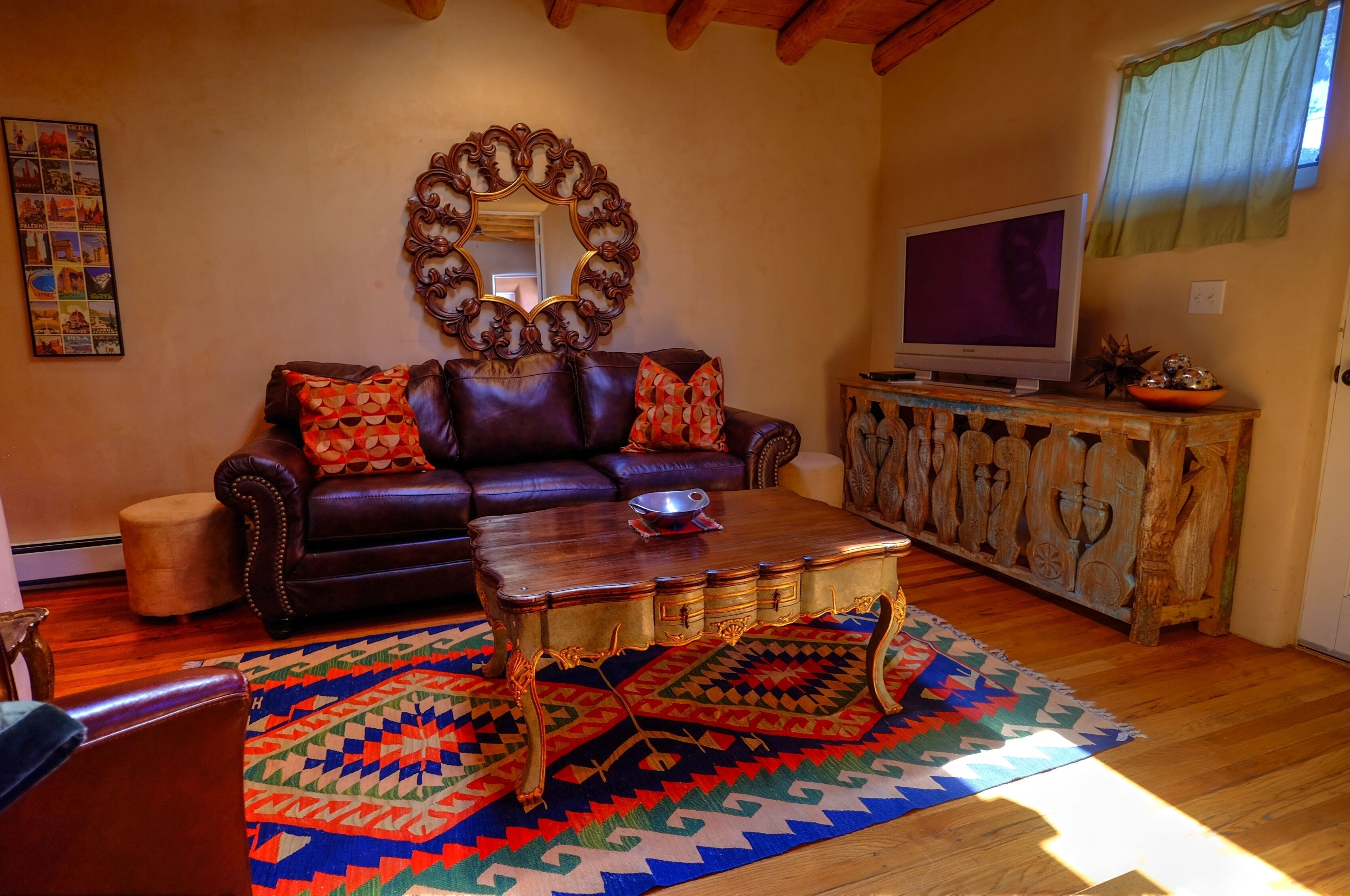 A living room with a leather sofa, a wooden coffee table, and a television on a wooden cabinet.