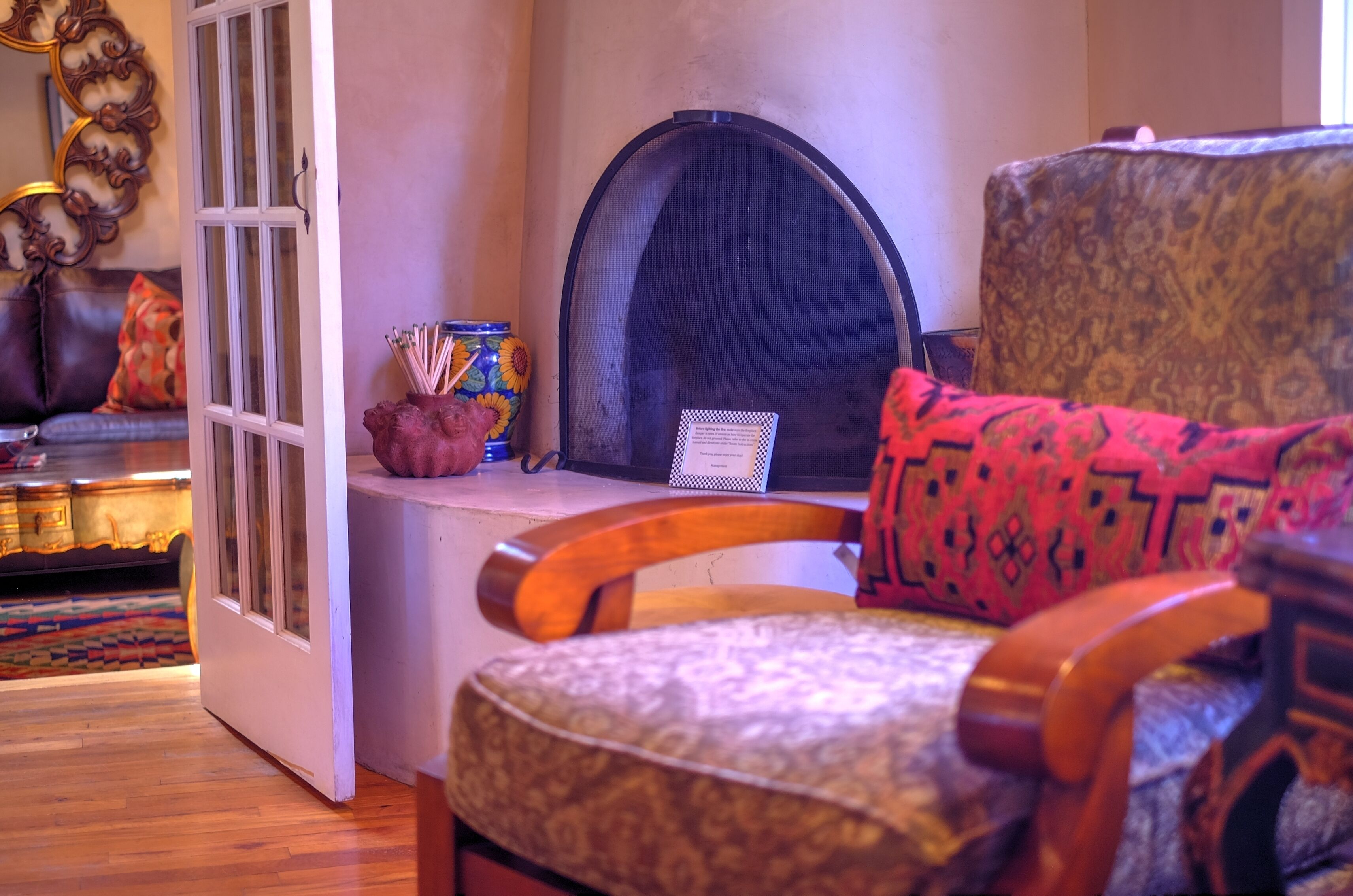 A living room with a fireplace, a patterned armchair, a wooden coffee table, and a decorative vase.