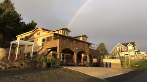 A two-story house with a stone facade, a balcony, and a covered porch. - Majestic View, Luxury Home, Corp Retreat, Sauna, Roads End (Lincoln City)