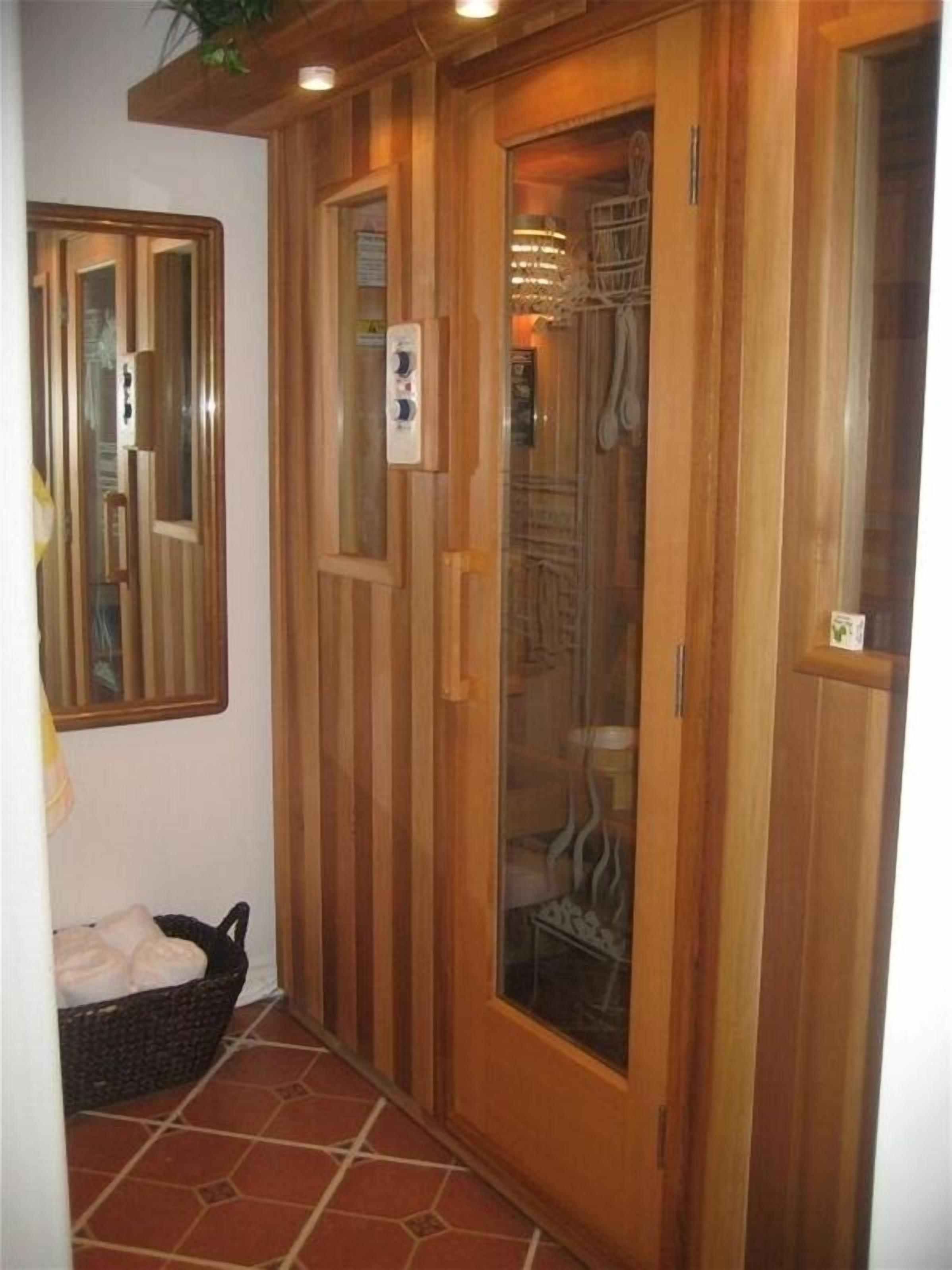 A wooden wardrobe with a glass door, a mirror, and a small basket on the floor.