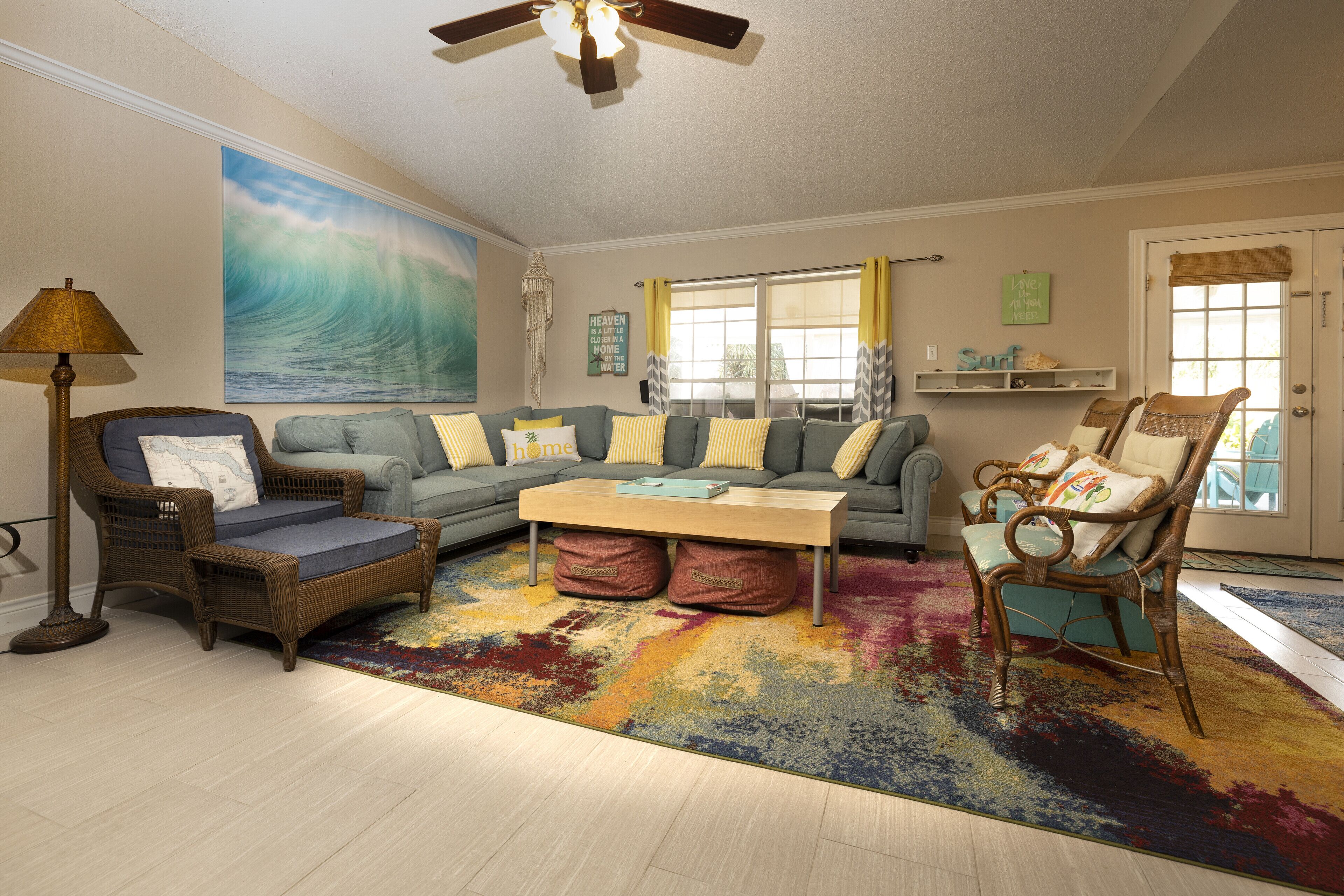 Ein Wohnzimmer mit einem großen Wandbild einer Welle, einer Couch, einem Couchtisch und zwei Sesseln.