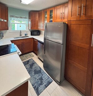 A kitchen with wooden cabinets, a stainless steel refrigerator, a microwave, and a toaster.