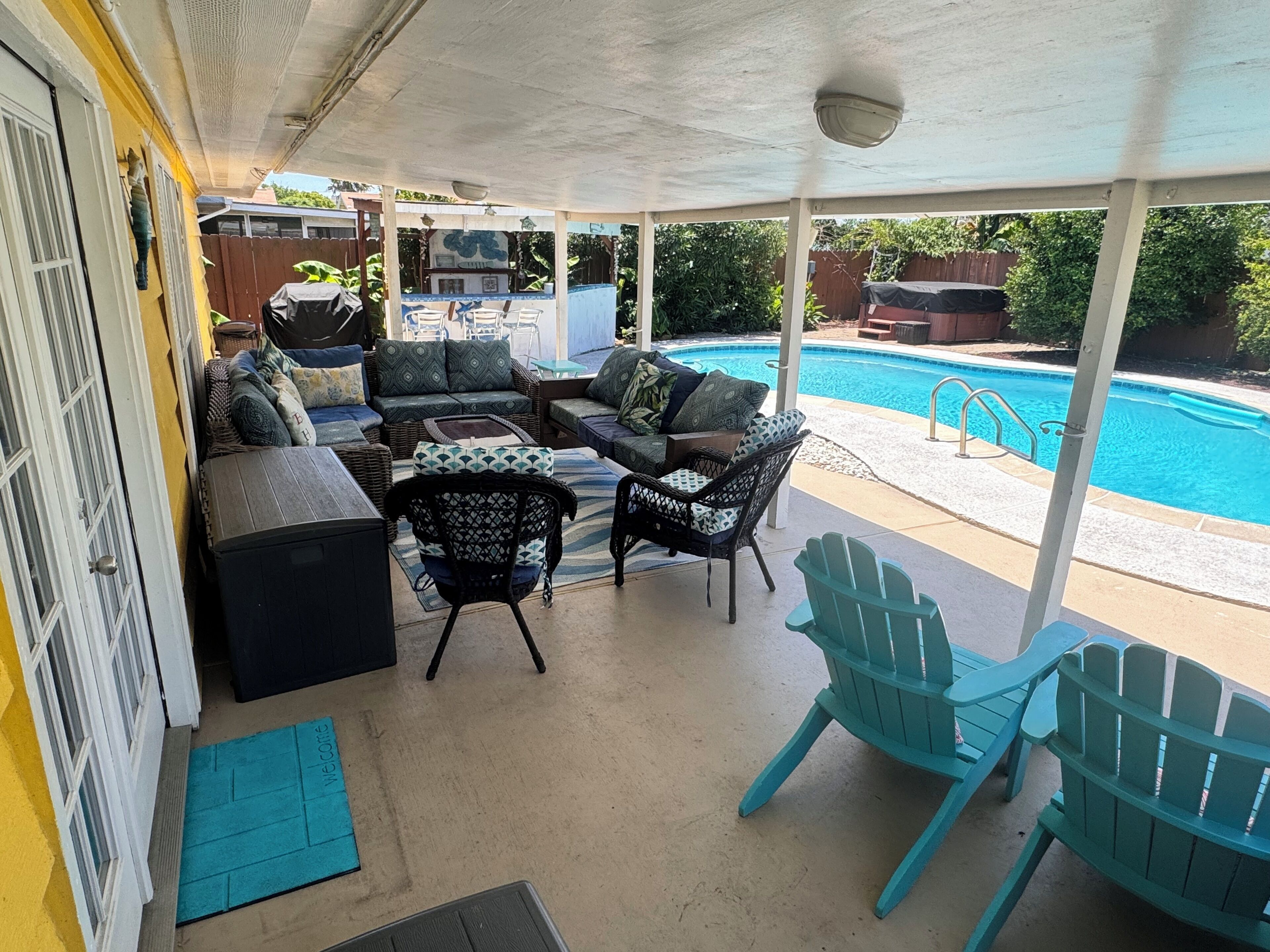 A covered patio with outdoor furniture, a pool, and a view of the backyard.