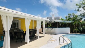 Ein überdachter Außenbereich mit Pool, Bar und Sitzgelegenheiten.