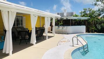 Ein überdachter Außenbereich mit Pool, Bar und Sitzgelegenheiten.