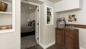 A bedroom with a bed, a nightstand, and a dresser. There is a door leading to another room. - Westside Cottage │Fenced Yards │Hot Tub │One Block to Galveston │Guest Favorite (Bend)