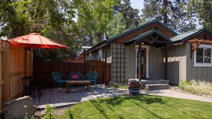 A wooden house with a covered patio, a stone pathway, and a fenced backyard. - Westside Cottage │Fenced Yards │Hot Tub │One Block to Galveston │Guest Favorite (Bend)