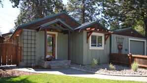 A single-story cottage with a front porch, a small window, and a garage. - Westside Cottage │Fenced Yards │Hot Tub │One Block to Galveston │Guest Favorite (Bend)