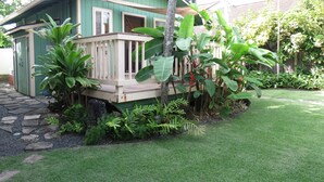 A small, single-story house with a wooden deck and a green exterior.