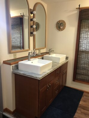 A bathroom with two sinks, a large mirror, and a clock on the wall. - Cottage-Very Close to Beach-Quiet A/C-Full Kitchen with Range/Oven-Deck-Laundry (Hauula)