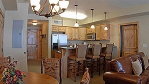 Una cocina amplia con armarios de madera, un comedor con mesa y sillas, y un sofá de cuero en la sala.
