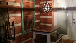 Una cocina rústica con una mesa y banco de madera, un lámpara colgante y una chimenea de piedra.