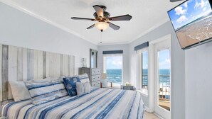 Ein Schlafzimmer mit Bett, Deckenventilator, Kommode und Meerblick.