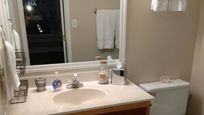 Ein Badezimmer mit Waschbecken, Spiegel, Toilette und Handtüchern.