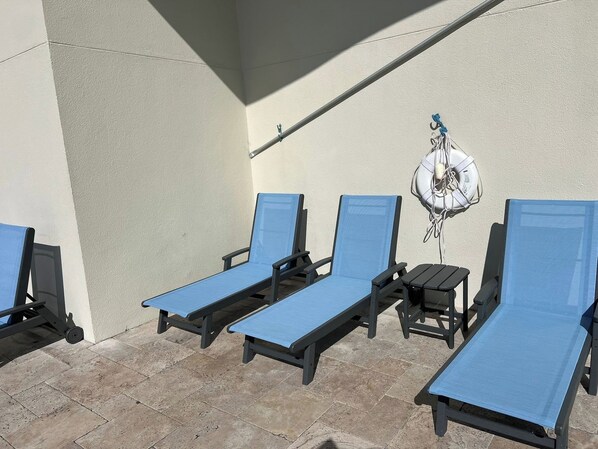 A set of three blue lounge chairs with black frames, arranged on a tiled patio area.