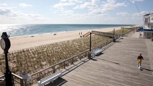 Une promenade de bord de mer avec une allée en bois, des bancs et un bâtiment doté d’un toit bleu.