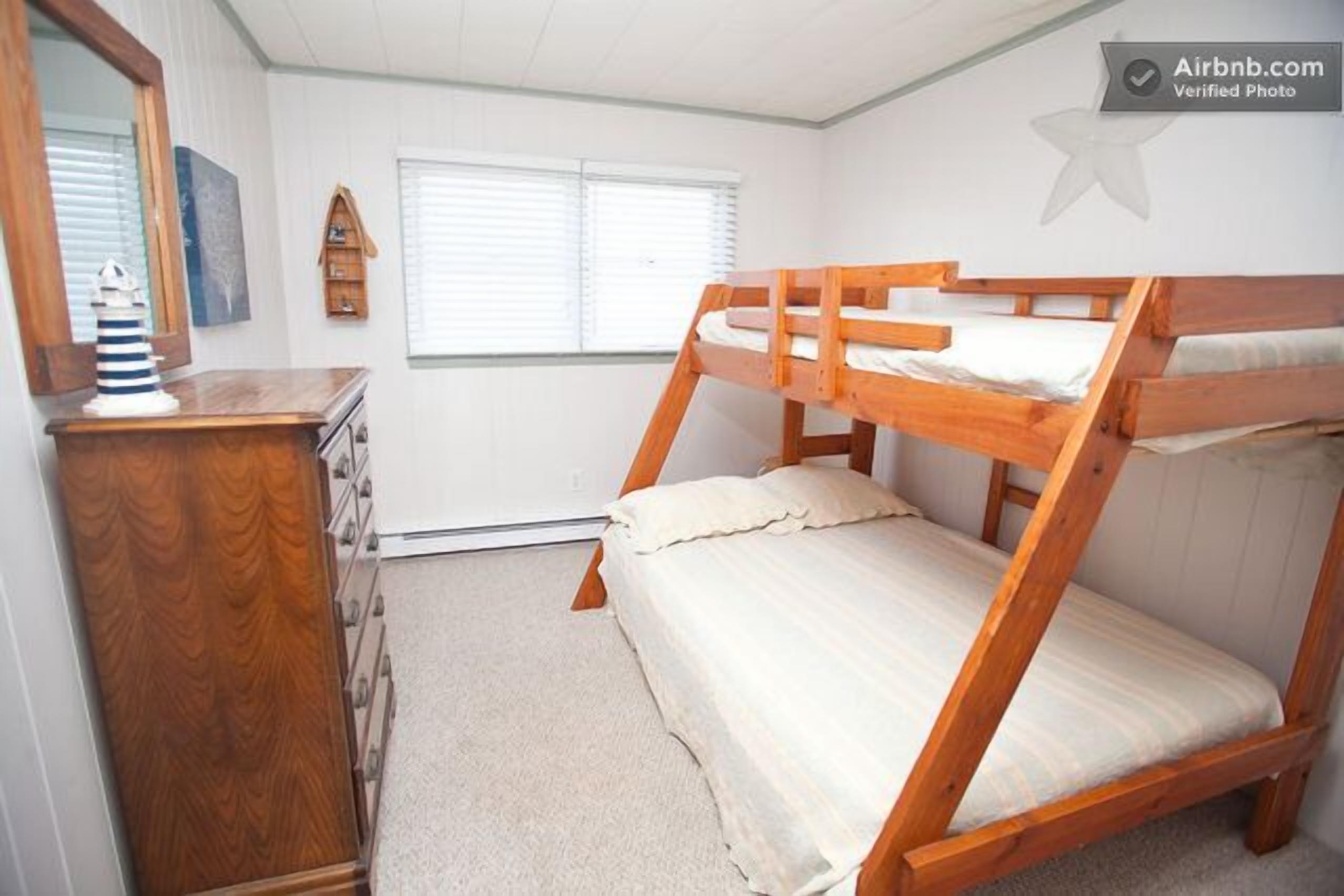 A bunk bed room with a dresser and a mirror.
